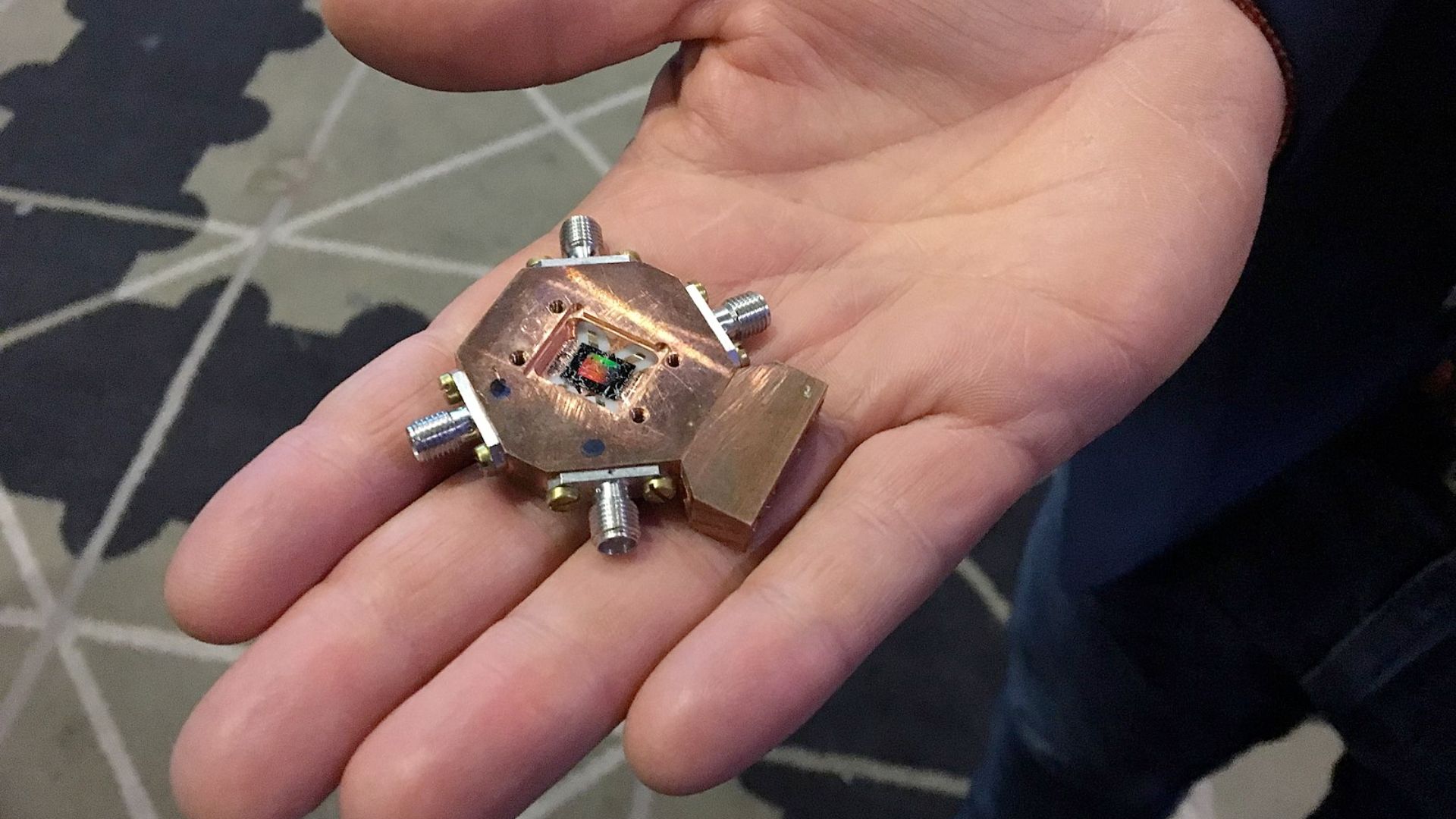 A 3 qubit quantum processor being held in one hand for scale.